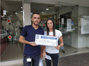 זוג צעיר מחזיקים מסמך לאחר סיום תהליך משכנתא מחוץ לסניף בנק